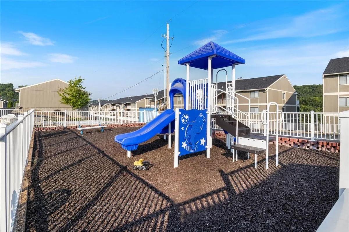 A bright and active outdoor playground scene, featuring modern playground equipment, a slide, and a fenced area. Children are seen playing, and families gather nearby, reflecting the section's emphasis on family-friendly fun and community engagement.