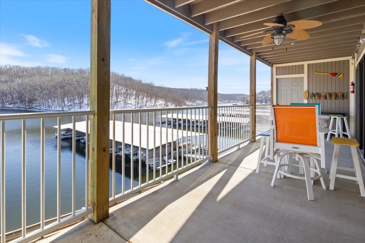 A cozy outdoor seating area overlooks a sweeping view of the lake, with colorful artwork adding to the inviting vibe. The warm lighting suggests it’s sunset, evoking the magic of evening strolls, boardwalk gatherings, and family barbecues by the water.