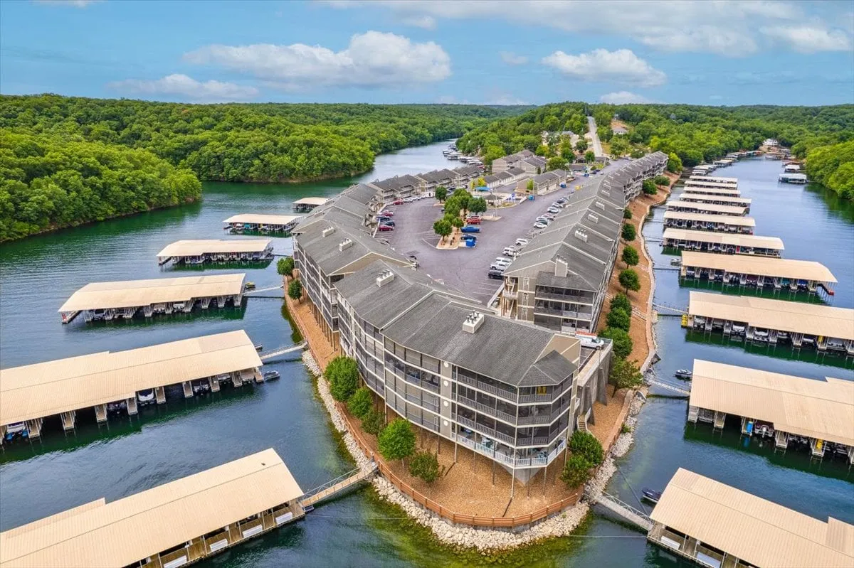 A scenic waterfront image showcasing a community dock, marinas, and lush greenery. The calm water and inviting dock highlight opportunities for boating, fishing, and water sports, while the surrounding condos set the scene for community living.