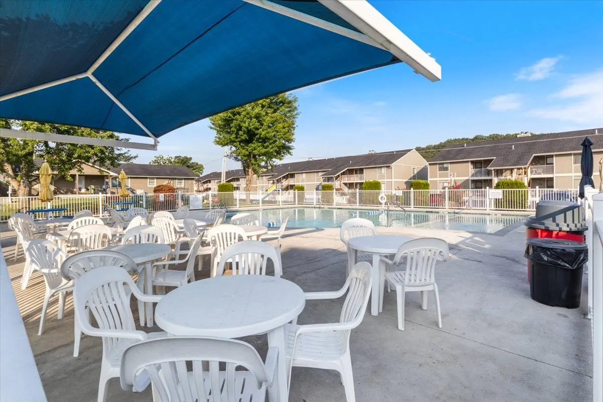 This cheerful exterior image centers on a sparkling swimming pool surrounded by outdoor seating and a shade structure, where families are enjoying themselves. Sunbathing, swimming, and socializing are clearly visible, with the inviting poolside area evoking the lively, communal atmosphere described in the section.