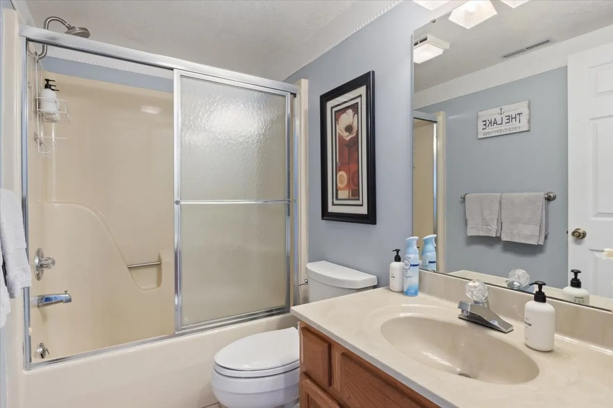 A stylish bathroom scene with a modern shower area, sink with accessories, framed artwork, and plush towels. The inviting setup hints at hotel-style amenities and a space meant for rejuvenation.